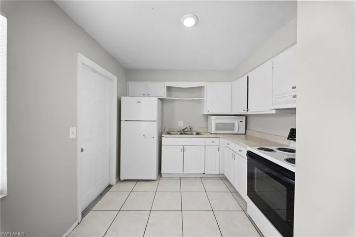 Kitchen featuring white appliances, white cabinetry, light countertops, open shelves, and light tile patterned floors