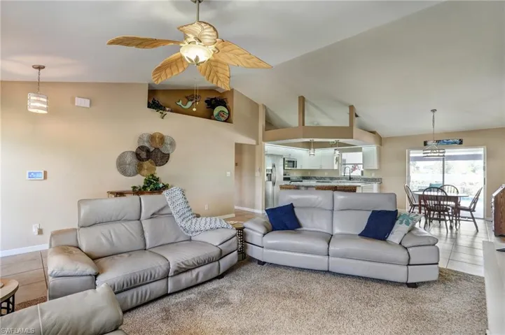 Living room featuring a ceiling fan, baseboards, light tile patterned floors, and high vaulted ceiling