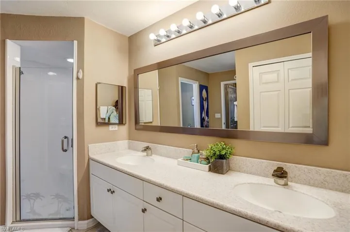Full bath featuring double vanity and a shower stall