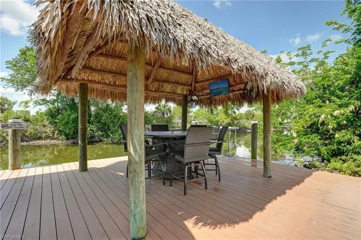 Wooden deck featuring a gazebo, a water view, and a dock