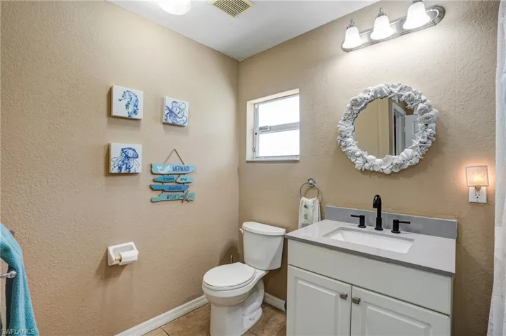Bathroom featuring toilet, vanity, tile patterned floors, and baseboards