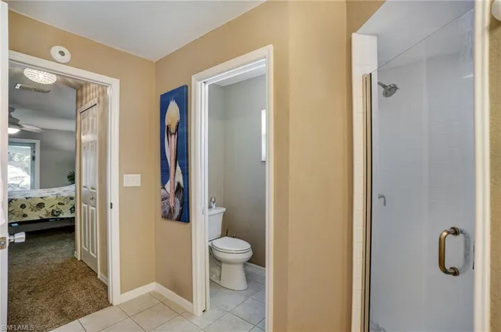 Full bathroom featuring ensuite bath, a stall shower, toilet, tile patterned floors, and baseboards