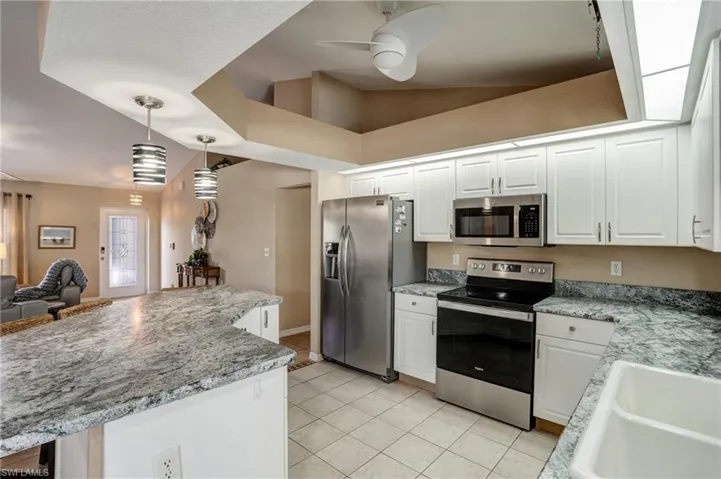 Kitchen featuring stainless steel appliances, ceiling fan, white cabinetry, and light tile patterned floors