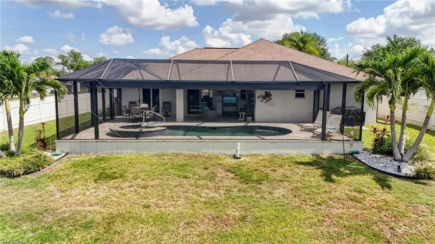 Rear view of house featuring a patio area, glass enclosure, and stucco siding