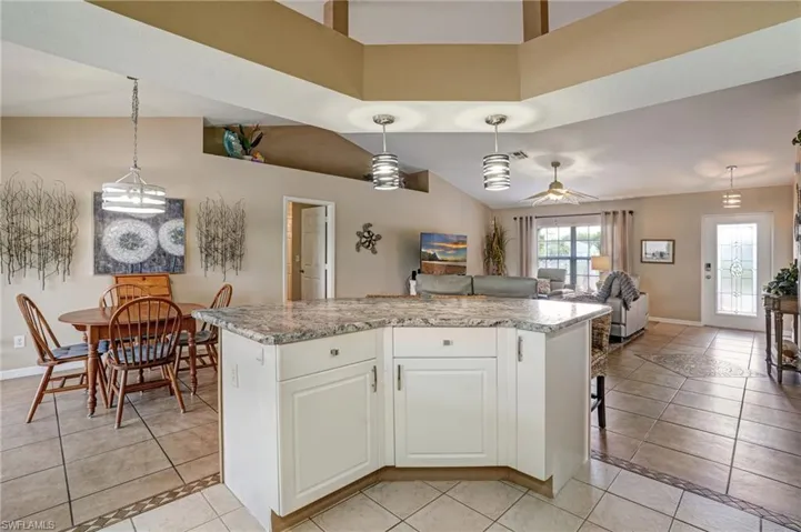 Kitchen featuring open floor plan, hanging light fixtures, baseboards, a center island, and white cabinetry