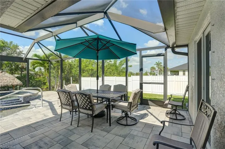 View of patio / terrace featuring an in-ground hot tub, outdoor dining space, and glass enclosure