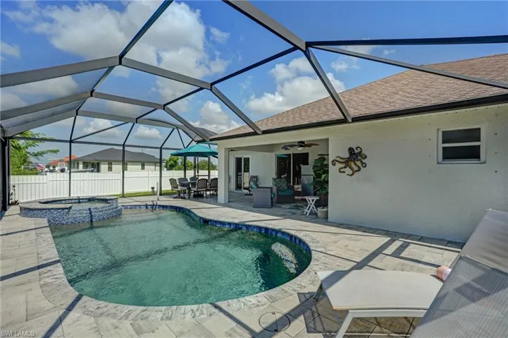 View of pool featuring a patio area, a ceiling fan, a pool with connected hot tub, a lanai, and outdoor dining area