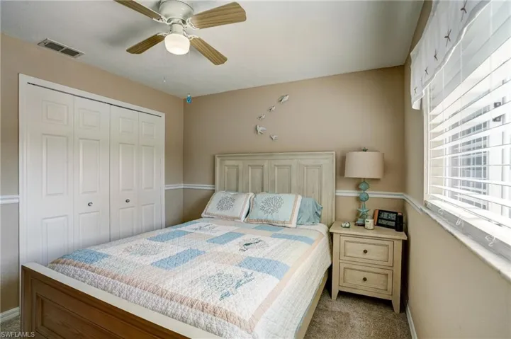 Bedroom with a closet, light carpet, baseboards, and a ceiling fan