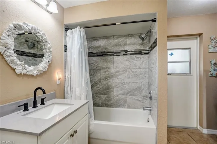 Full bathroom featuring shower / bath combination with curtain, vanity, and tile patterned flooring
