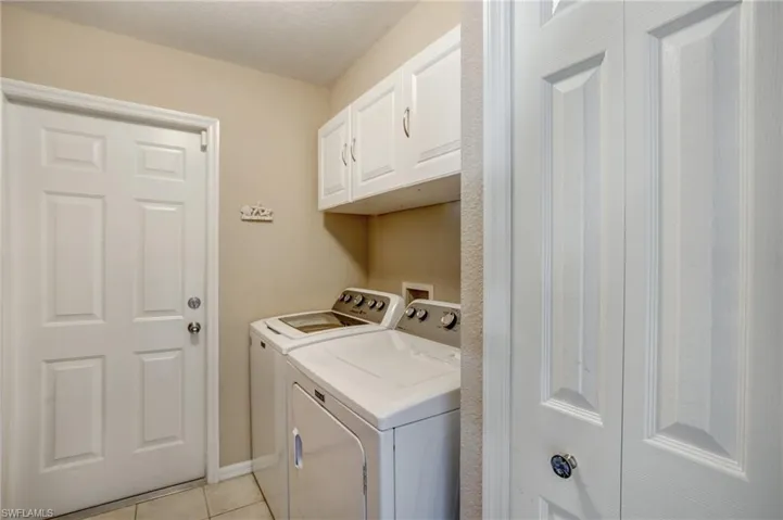 Laundry room with washer and clothes dryer, cabinet space, and light tile patterned floors