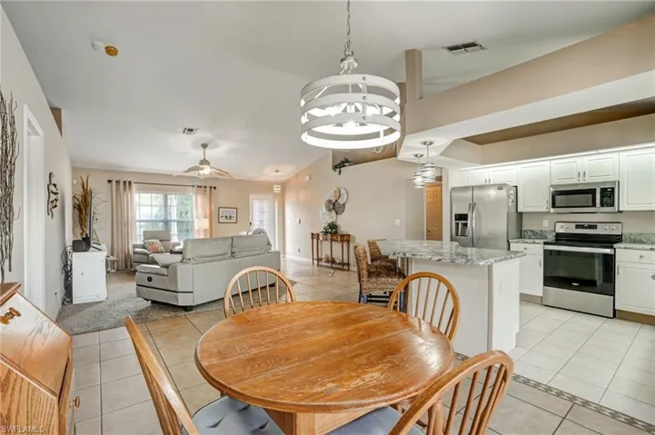 Dining space with light tile patterned flooring, inlaid floor details, a ceiling fan, a chandelier, and baseboards