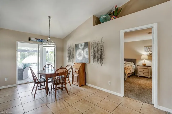 Dining room with lofted ceiling, light tile patterned floors, and baseboards