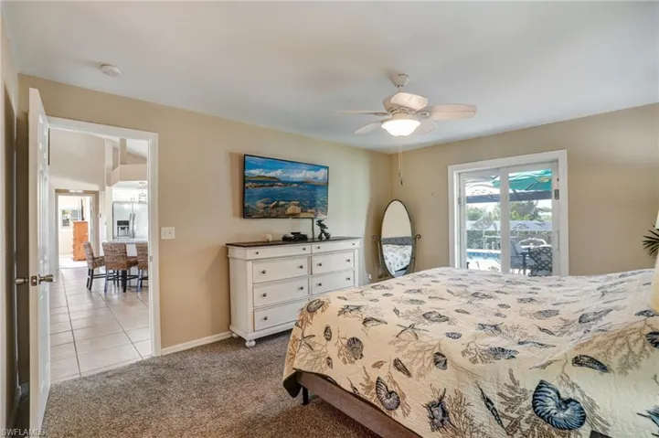 Bedroom featuring baseboards, carpet, ceiling fan, tile patterned floors, and stainless steel refrigerator with ice dispenser