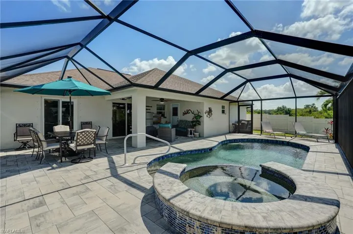 View of pool featuring a ceiling fan, a patio area, a pool with connected hot tub, outdoor dining area, and a lanai