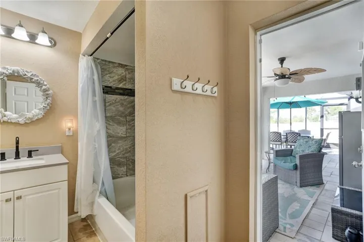 Bathroom featuring a ceiling fan, vanity, shower / bath combo with shower curtain, tile patterned floors, and a textured wall