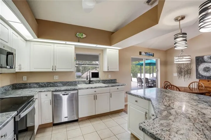 Kitchen featuring appliances with stainless steel finishes, a sink, light tile patterned floors, and white cabinets