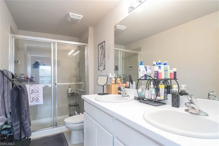 Bathroom featuring vanity, a shower with shower door, and toilet