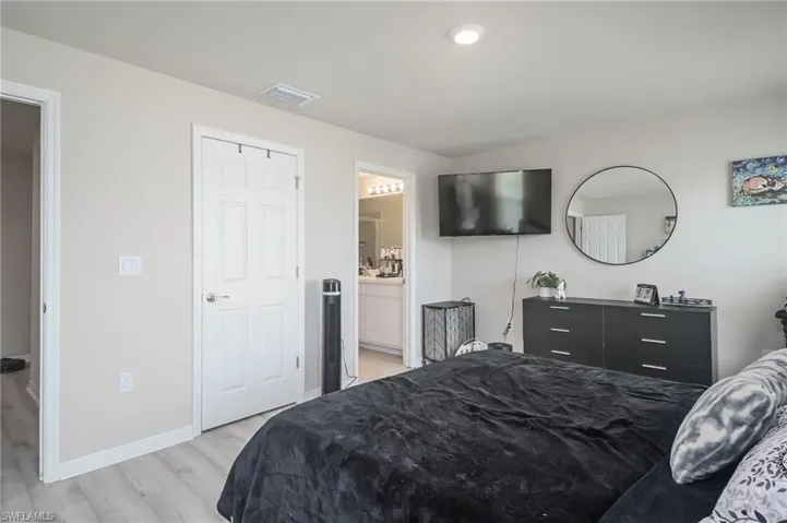 Bedroom with connected bathroom and light wood-type flooring