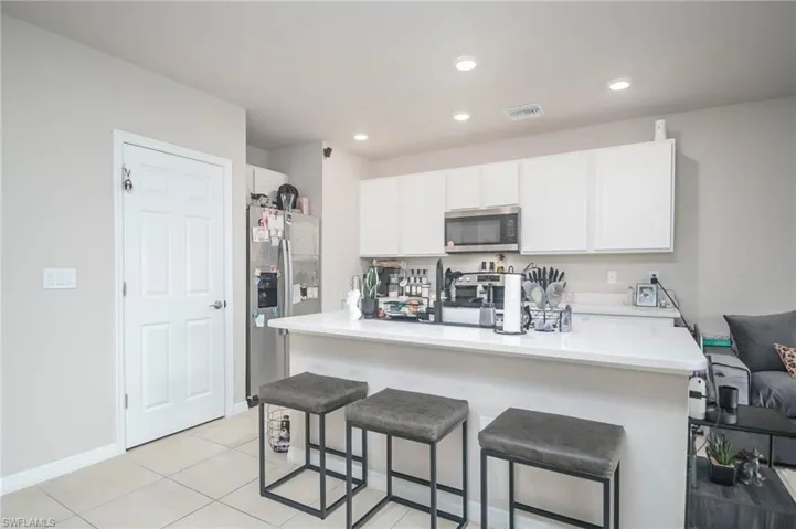 Kitchen featuring stainless steel appliances, light tile patterned flooring, a breakfast bar area, and white cabinets