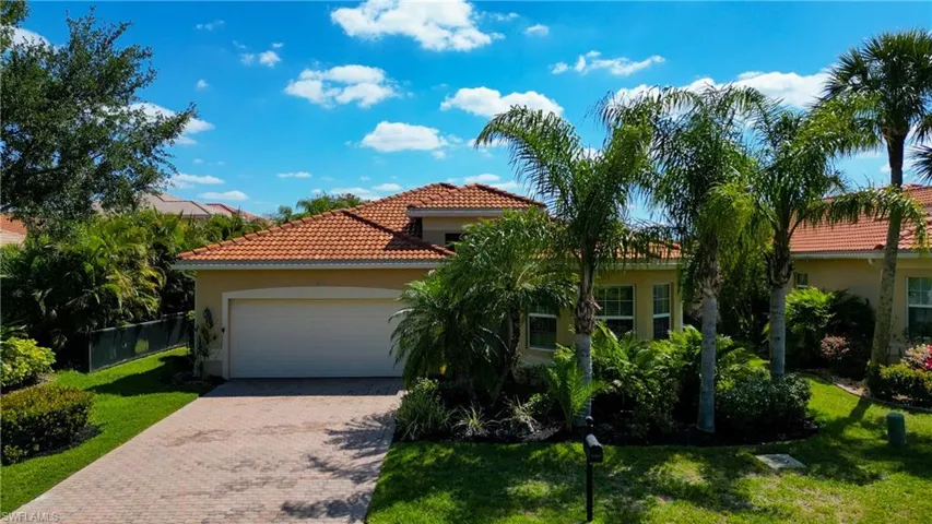 Mediterranean / spanish-style house featuring a tile roof, decorative driveway, a garage, a front yard, and stucco siding