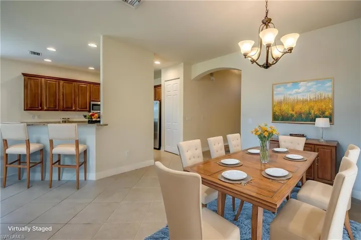 Dining space with light tile patterned flooring, arched walkways, an inviting chandelier, visible vents, and recessed lighting