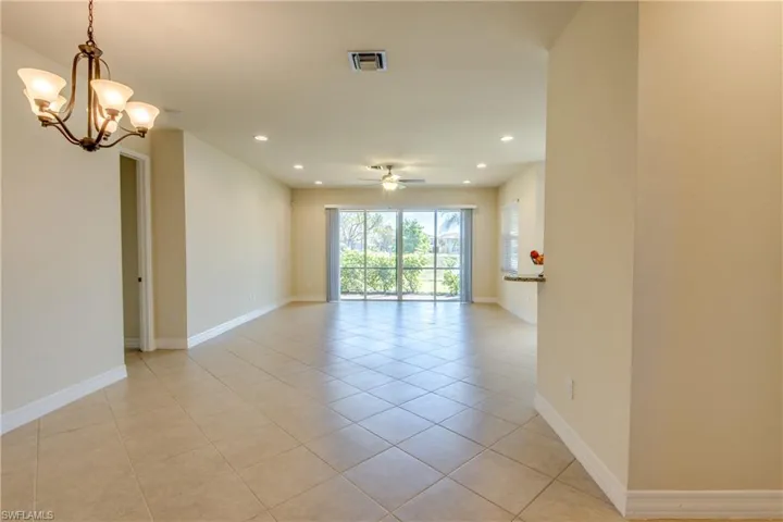 Unfurnished room featuring recessed lighting, visible vents, light tile patterned floors, baseboards, and ceiling fan with notable chandelier