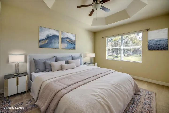 Carpeted bedroom with baseboards, a ceiling fan, and a tray ceiling