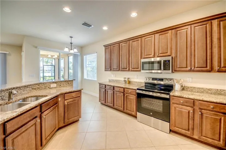 Kitchen with brown cabinetry, visible vents, appliances with stainless steel finishes, and a sink