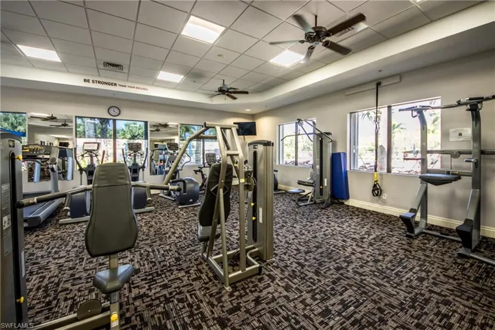 Exercise room featuring a drop ceiling, visible vents, a ceiling fan, baseboards, and carpet flooring