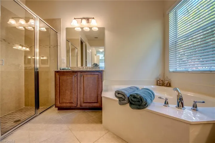 Bathroom featuring a bath, a shower stall, tile patterned flooring, and plenty of natural light