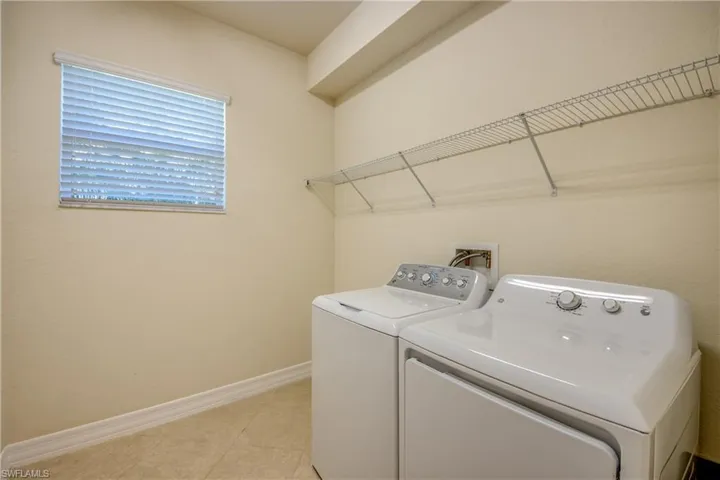 Washroom with washing machine and dryer, baseboards, laundry area, and light tile patterned floors