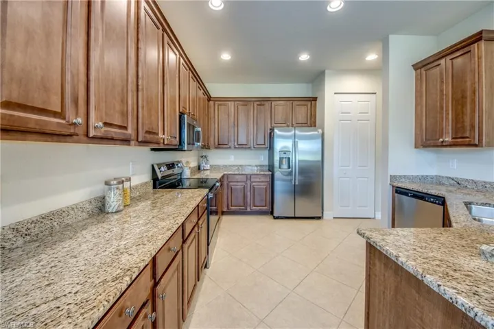 Kitchen featuring light tile patterned flooring, light stone countertops, stainless steel appliances, and recessed lighting