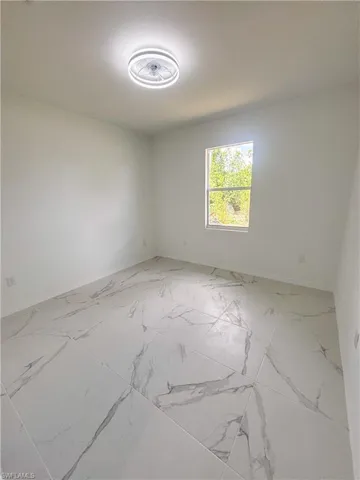 Spare room featuring baseboards and marble finish flooring