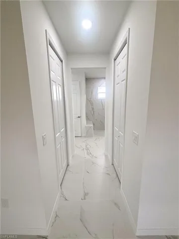 Corridor with light marble finish floors and baseboards
