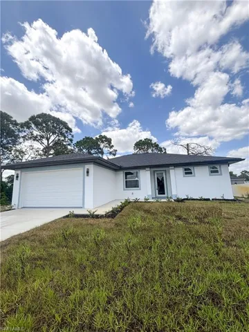View of front facade with concrete driveway, an attached garage, stucco siding, and a front yard