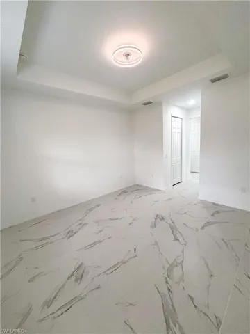 Unfurnished room featuring a raised ceiling and baseboards
