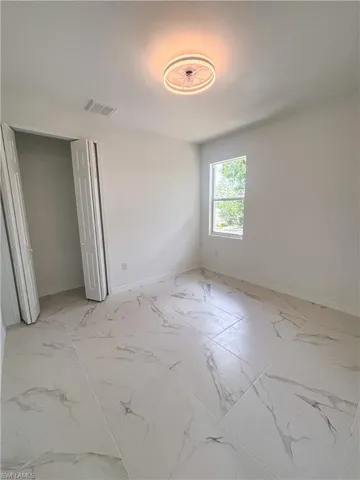 Unfurnished bedroom with light marble finish floors, baseboards, and a closet