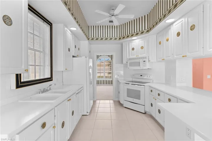 Kitchen featuring light countertops, white cabinetry, white appliances, a ceiling fan, and light tile patterned floors