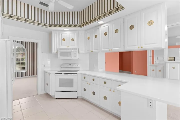 Kitchen featuring white appliances, white cabinetry, light countertops, a ceiling fan, and light tile patterned floors