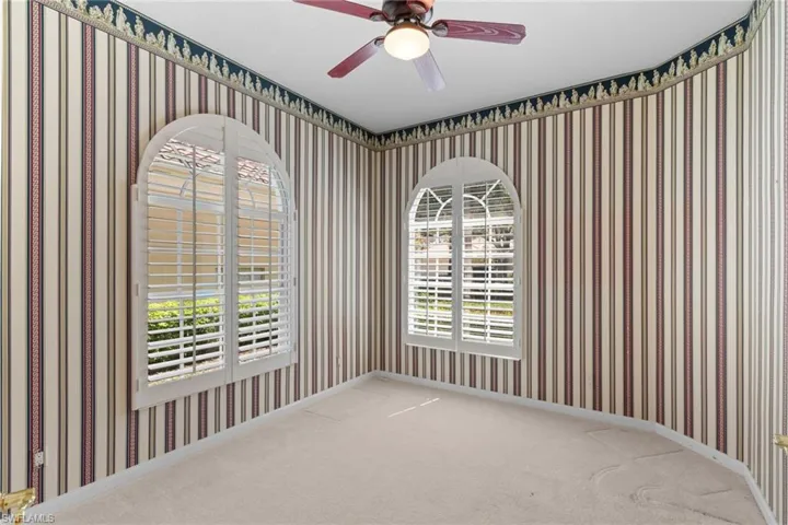 Empty room featuring wallpapered walls, a ceiling fan, and light colored carpet