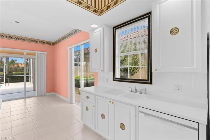 Kitchen with backsplash, light countertops, dishwasher, white cabinetry, and light tile patterned flooring