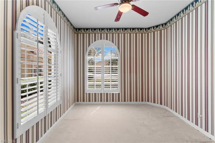 Unfurnished room featuring wallpapered walls, light colored carpet, and ceiling fan
