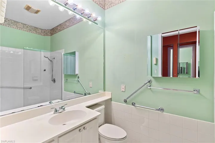 Bathroom with vanity, walk in shower, tile walls, and wainscoting