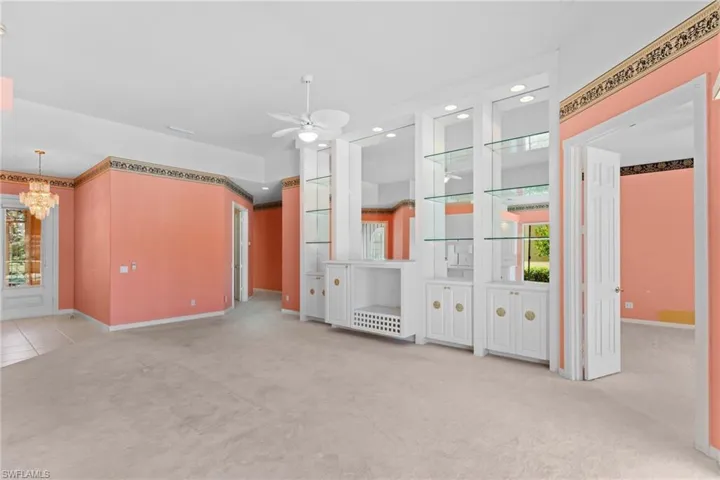 Unfurnished living room featuring light colored carpet, ceiling fan, and hanging lights
