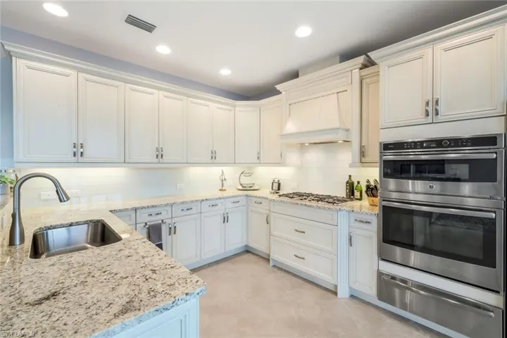 Kitchen featuring double oven, a warming drawer, tasteful backsplash, recessed lighting, and custom range hood