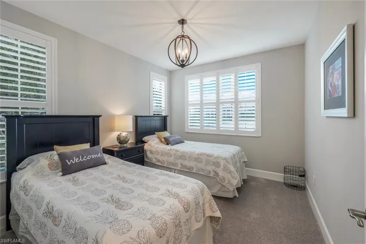 Carpeted bedroom with baseboards and a chandelier
