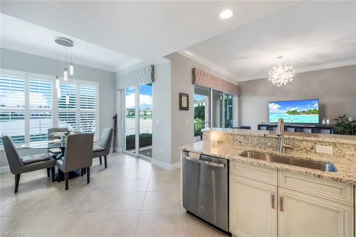 Kitchen featuring crown molding, stainless steel dishwasher, a chandelier, plenty of natural light, and hanging light fixtures