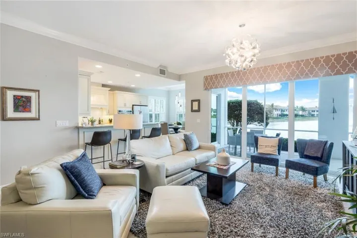 Living room with crown molding, a chandelier, a water view, and recessed lighting