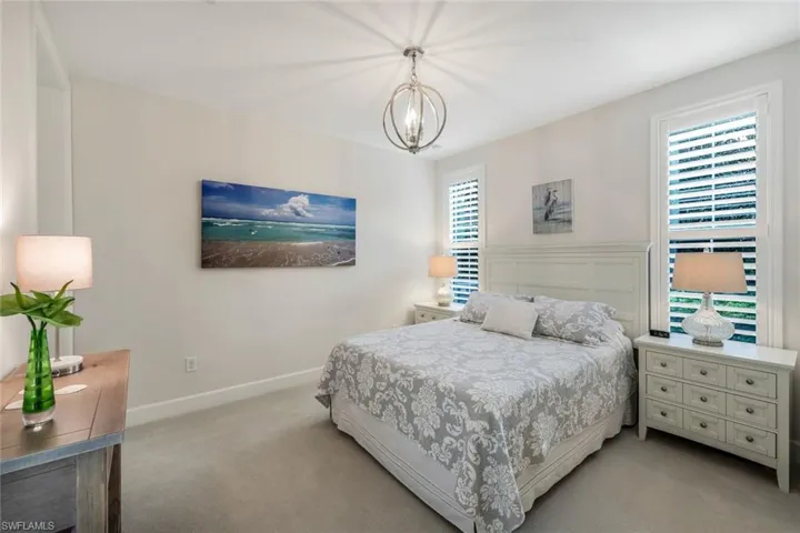 Bedroom featuring light colored carpet and a chandelier