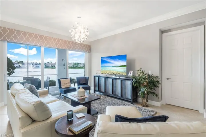 Living area featuring ornamental molding, light tile patterned floors, and a chandelier